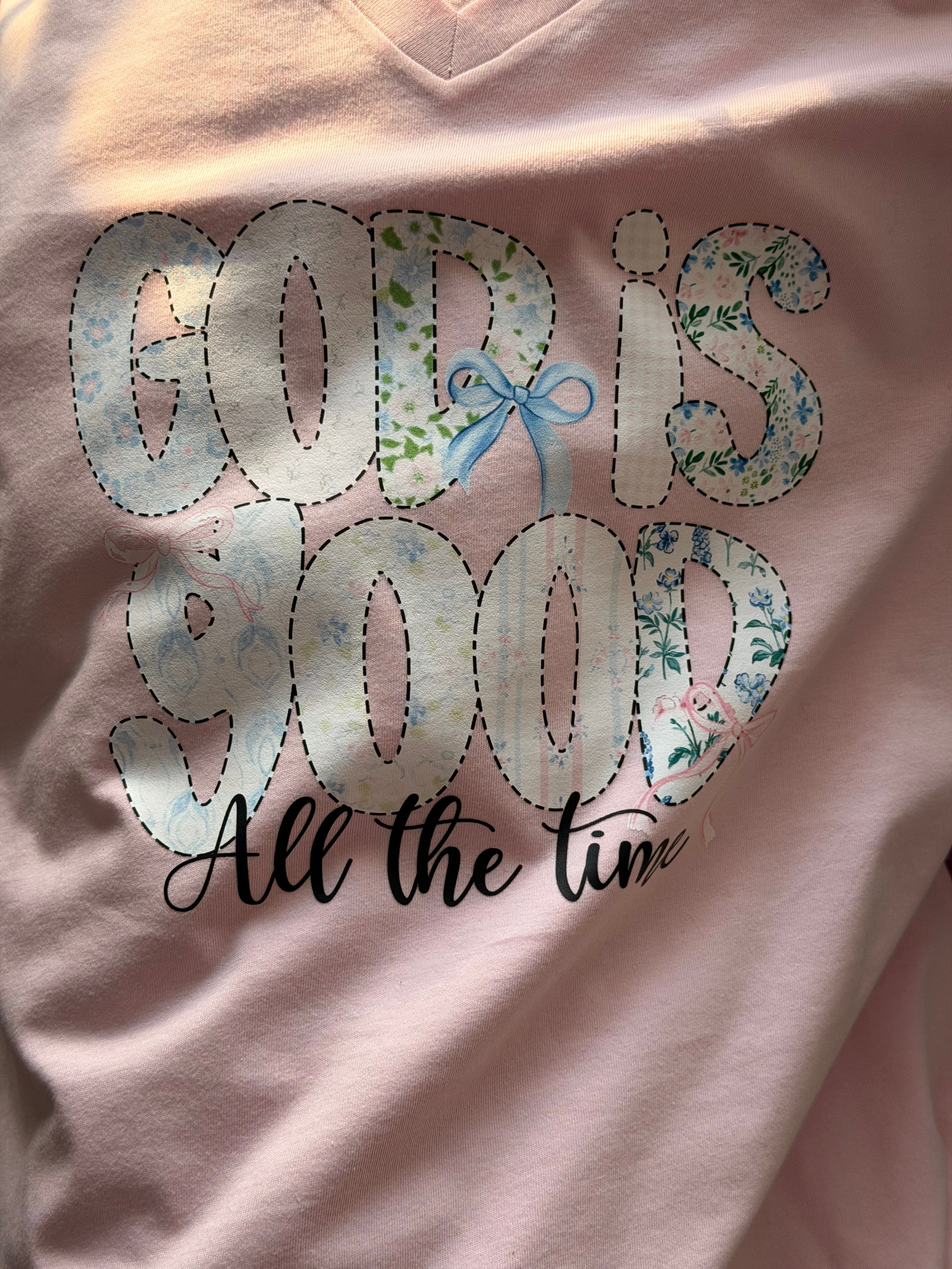 Pink shirt with 'God is Good All the Time' text and floral design.